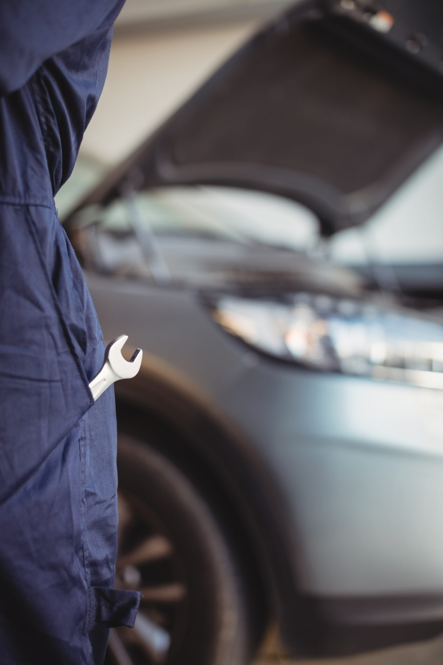 Mid-section of mechanic with a wrench tool in pocket at garage